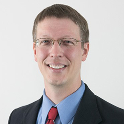Bern Jordan, a white man with brown hair wearing glasses, a suit, and a smile.