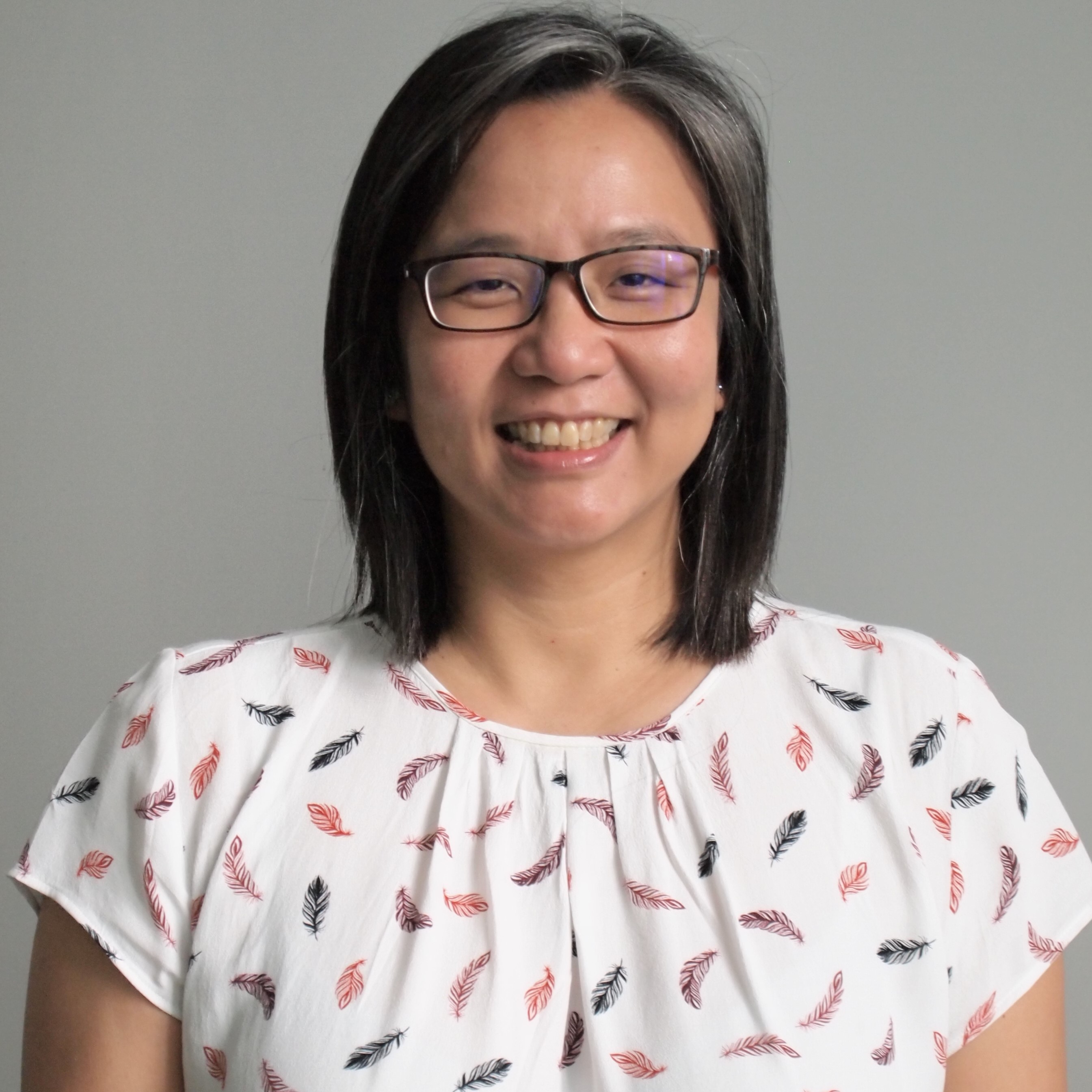 Pin Sym Foong, an Asian woman with medium lengthhair, wearing rectangular-shape eyeglasses and a colourful scarf