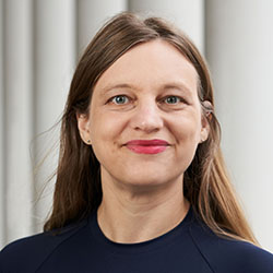 Maria Wolters, a white woman with long dark blonde hair and blue eyes, in a navy t-shirt, smiling with closed mouth